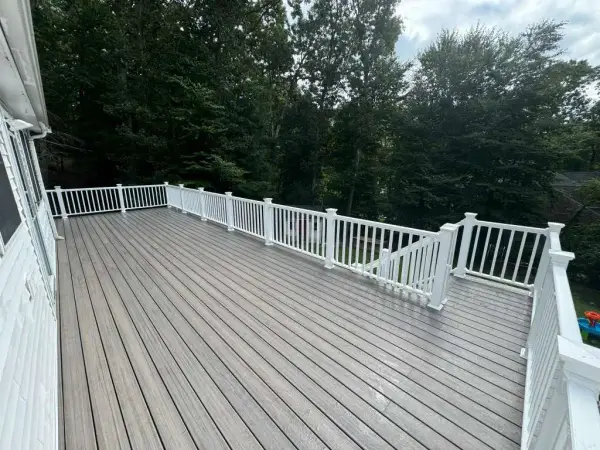 Elevated backyard composite deck with white railings in Bellingham, MA